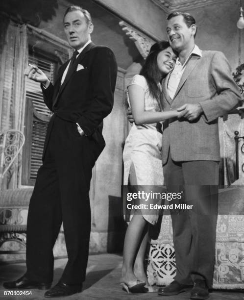 American actor William Holden with his arm around actress France Nuyen on the set of the film 'The World of Suzie Wong' at the MGM studios in...