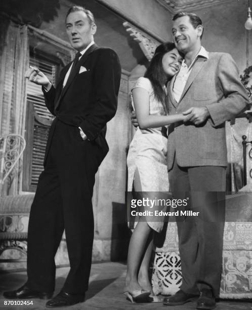 American actor William Holden with his arm around actress France Nuyen on the set of the film 'The World of Suzie Wong' at the MGM studios in...