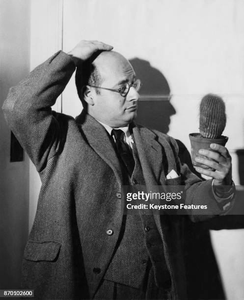 Musician and comic Gerard Hoffnung contemplates a cactus at his home in Golders Green, London, January 1959.