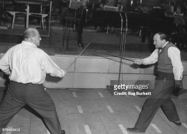 Musician and comic Gerard Hoffnung duels with pianist Joseph Cooper during rehearsals for Hoffnung's 'Interplanetary Music Festival' at the Royal...