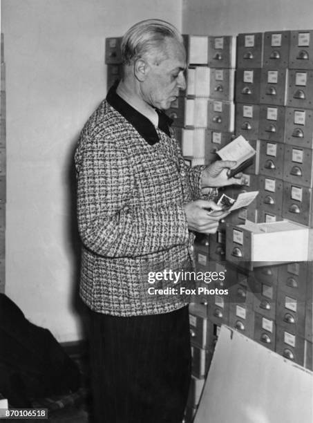 Heinrich Hoffmann , official photographer to Adolf Hitler, at work on his files after the war, circa 1946. He destroyed them and is having to...