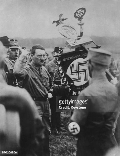 German Nazi Party leader Adolf Hitler hands over the Sturmabteilung emblem to to one of his leaders during a mass rally at Braunschweig or Brunswick,...