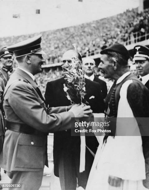 German Chancellor Adolf Hitler receives the Olympic Olive Branch from Spyridon Louis at the Olympic Stadium, at the opening of the Berlin Olympics,...