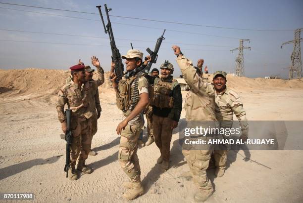 Iraqi forces dance on November 4, 2017 near the Syrian border after recapturing the border town of Qaim, west of Anbar, from the Islamic State group...