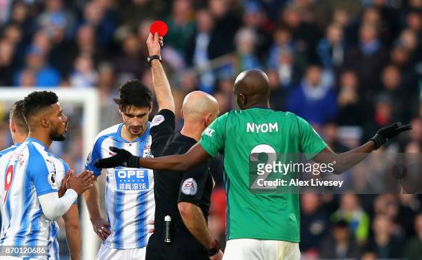 Christopher Schindler of Huddersfield Town is shown a red card by referee Roger East during the Premier League match between Huddersfield Town and...