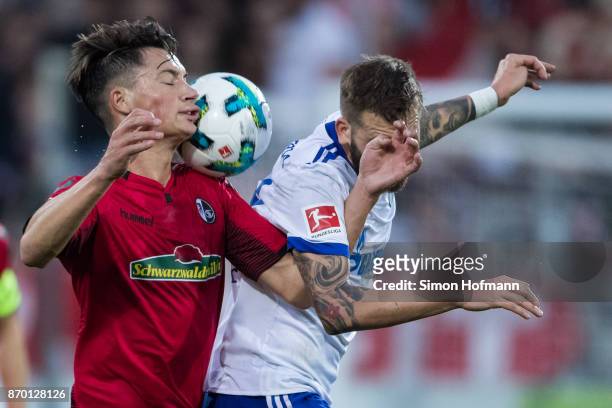 Pascal Stenzel of Freiburg jumps for a header with Guido Burgstaller of Schalke during the Bundesliga match between Sport-Club Freiburg and FC...