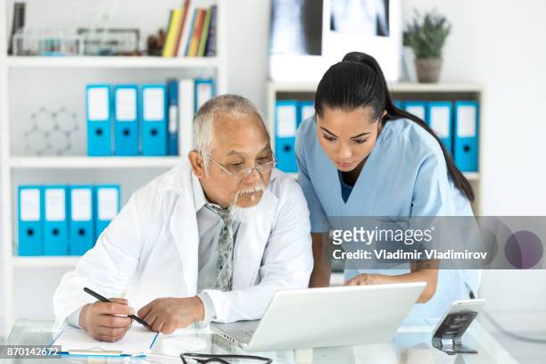 médicos especialistas usando laptop no armário - artigo da imprensa - fotografias e filmes do acervo
