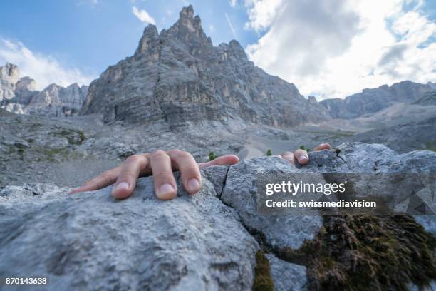 human hands gripping last rock on mountain summit - reaching the end stock pictures, royalty-free photos & images