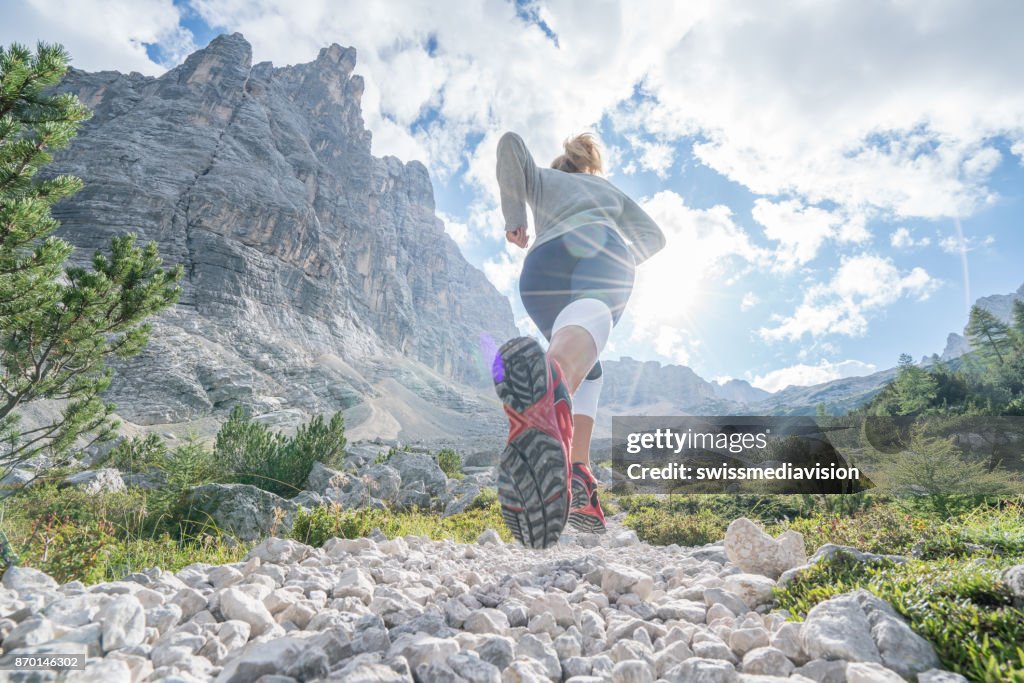 Young equipado trilha de mulher correndo nas Dolomitas, Itália