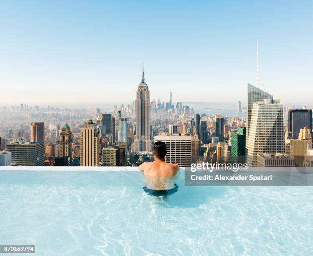 young man relaxing in a swimming pool with view towards new york city skyline - holiday tourist usa stock-fotos und bilder