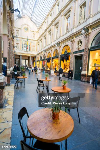 bistrot table and chairs outside the entrance of a movie theater under the glass-roofed of galeries royales saint-hubert, one of arcade galleries in brussels, belgium galeries royales saint-hubert, one of arcade galleries in brussels, belgium - st hubert galleries stock-fotos und bilder