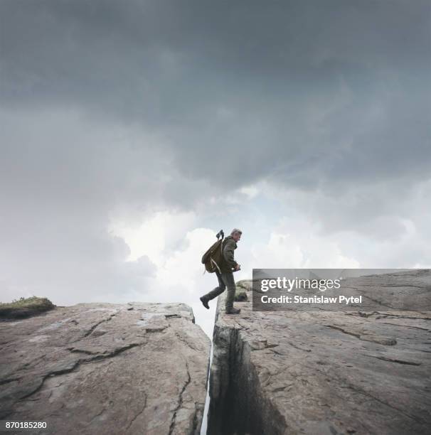 man trekking, crossing chasm in mountains - abyss stock pictures, royalty-free photos & images