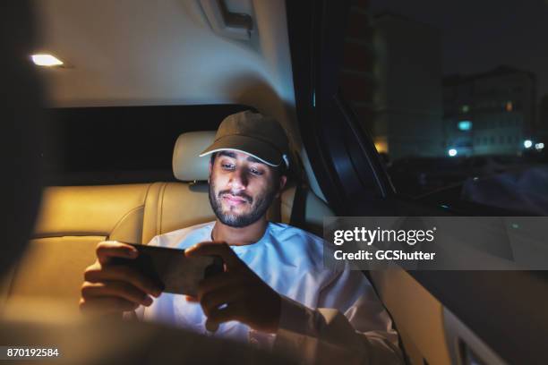 streaming voetbal op een slimme telefoon tijdens het rijden van een auto - people from oman stockfoto's en -beelden