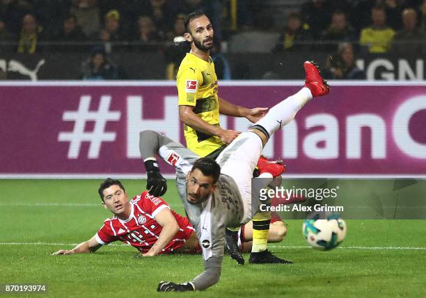 Robert Lewandowski of Bayern Muenchen Oemer Toprak of Dortmund and Roman Buerki of Dortmund look after the ball as Muenchen score their third goal to...