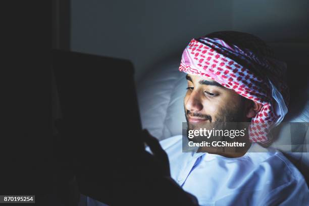 het lezen van een ebook's avonds laat, alvorens naar bed te gaan. - reading v oman stockfoto's en -beelden