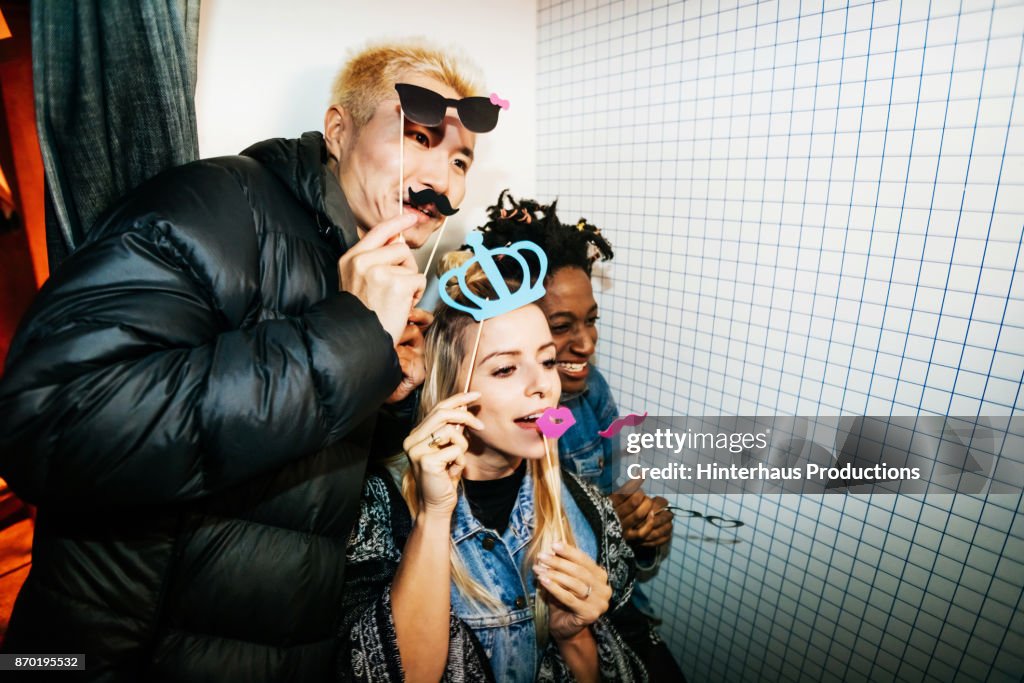 Friends Taking Silly Pictures In Photo Booth At Open Air Nightclub