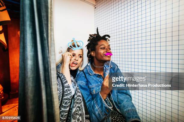 two friends taking pictures in photo booth on night out together - carefree stock pictures, royalty-free photos & images