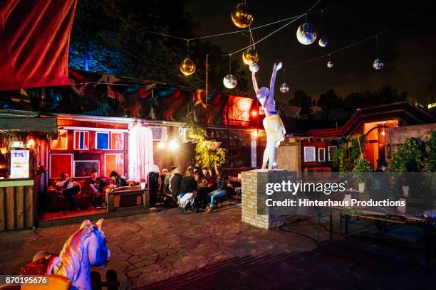 colourful scene at open air nightclub with people sitting down, drinking and chatting - berlin night stock-fotos und bilder