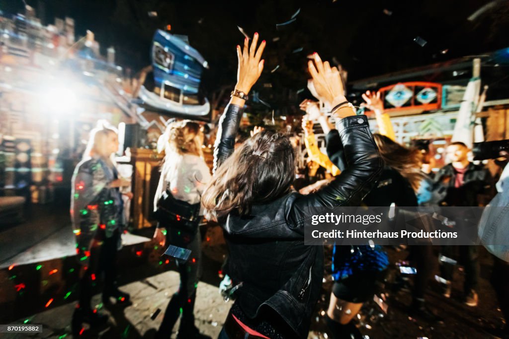 Young Woman Throwing Hands In Air While Dancing At Open Air Nightclub