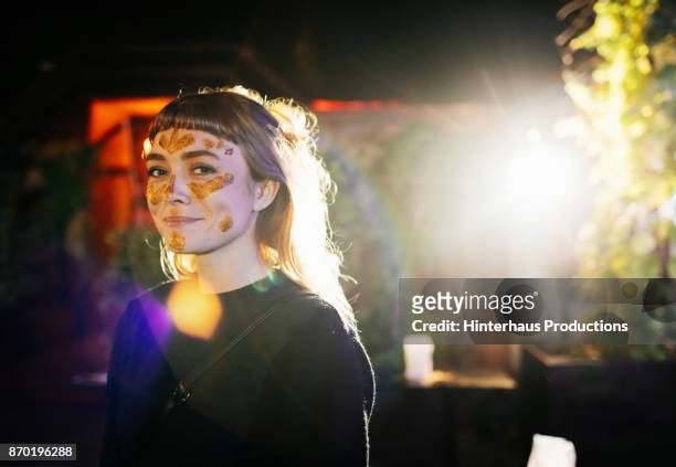 smiling girl with gold glitter face paint at nightclub - rave stock-fotos und bilder