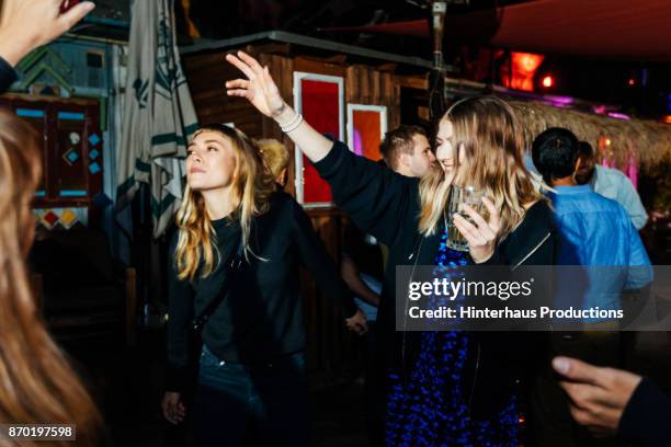 girl raising hand in the air while dancing at nightclub with friends - young women only stock-fotos und bilder