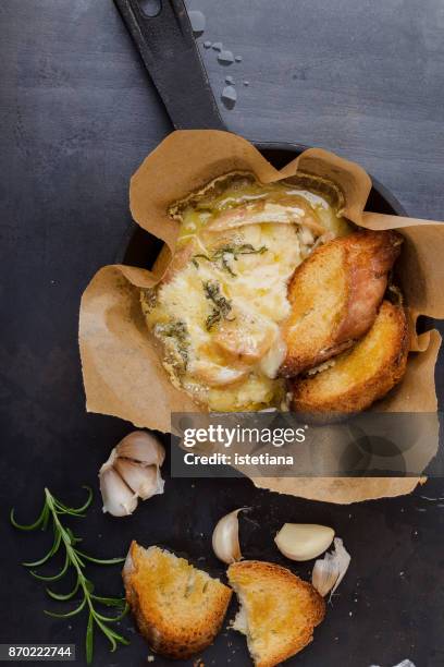 baked cheese with garlic and rosemary in cast iron skillet - melting pot foto e immagini stock