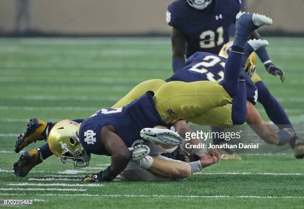 John Wolford of the Wake Forest Demon Deacons is flattened by Shaun Crawford and Drue Tranquill of the Notre Dame Fighting Irish at Notre Dame...