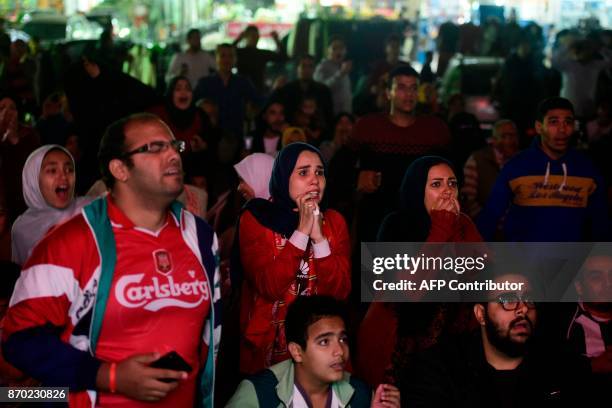 Egyptian football fans react as they watch from the outskirts of Cairo the CAF Champions League final football match between Egypt's Al-Ahly and...