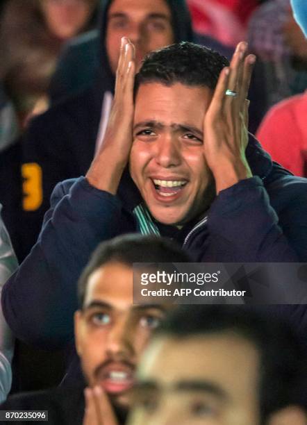 Egyptian football fans react as they watch from the outskirts of Cairo the CAF Champions League final football match between Egypt's Al-Ahly and...