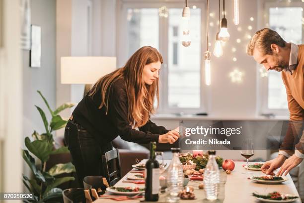 couple arranging dining table with christmas decoration - christmas feast stock pictures, royalty-free photos & images