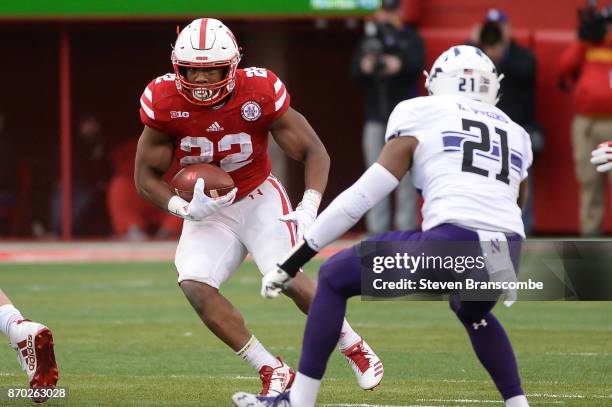 Running back Devine Ozigbo of the Nebraska Cornhuskers runs against safety Kyle Queiro of the Northwestern Wildcats at Memorial Stadium on November...