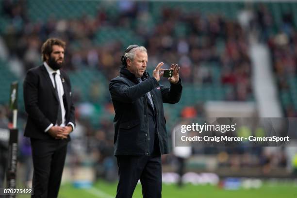 Former New Zealand hooker Sean Fitzpatrick takes a picture of the warm up drills on his phone before the Killik Cup match between Barbarians and New...