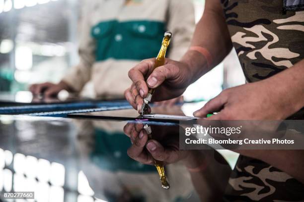 a worker uses a glass cutter while working with a sheet of glass - glass cutter fotografías e imágenes de stock