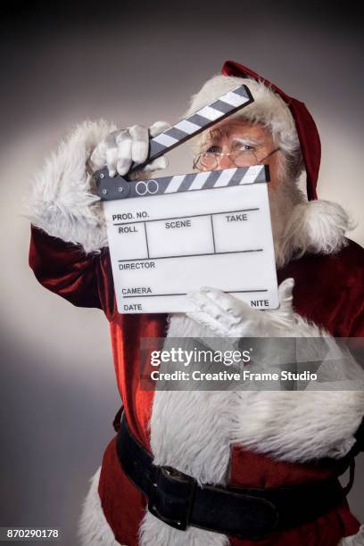 shy santa claus holding a film clapperboard to cover his face up - christmas movie stock pictures, royalty-free photos & images