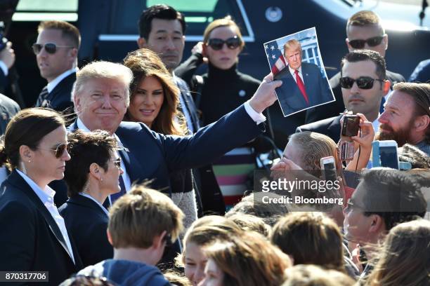 President Donald Trump, third left, holds a photograph of himself while U.S. First Lady Melania Trump, fourth left, looks on as they greet attendees...