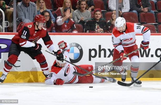 Josh Jooris of the Carolina Hurricanes and Brendan Perlini of the Arizona Coyotes battle for control of the puck as Marcus Kruger of the Hurricanes...