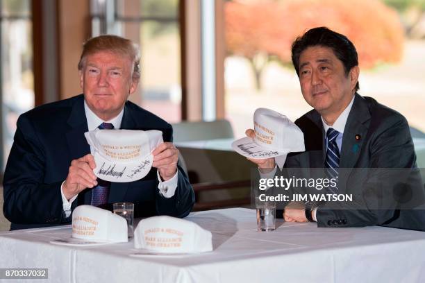 President Donald Trump holds up a hat with Japan's Prime Minister Shinzo Abe during a luncheon at the Kasumigaseki Country Club Golf Course in...