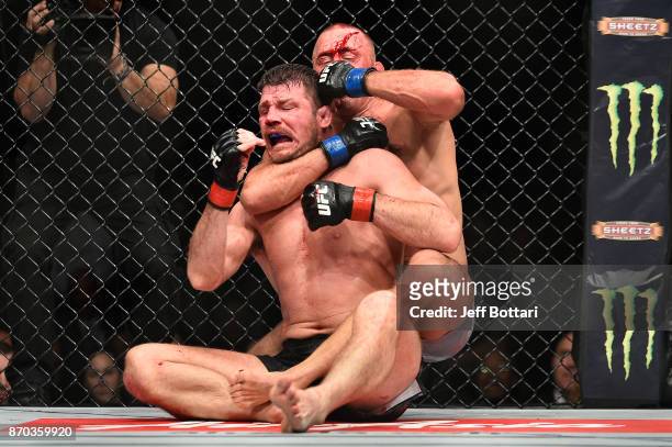 Georges St-Pierre of Canada brings down Michael Bisping of England in their UFC middleweight championship bout during the UFC 217 event at Madison...