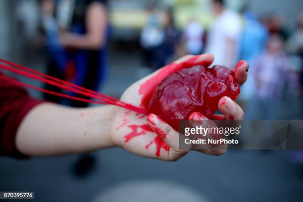 Woman holds a heart during the annual procession of zombies in Mexico City on November 4, 2017. Hundreds dressed in rags and ghoulish makeup to look...