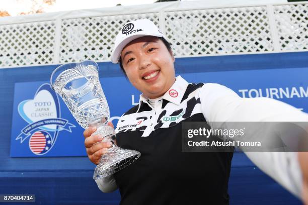 Shanshan Feng of China imitates a selfie as she poses with the trophy after winning the TOTO Japan Classics 2017 at the Taiheiyo Club Minori Course...