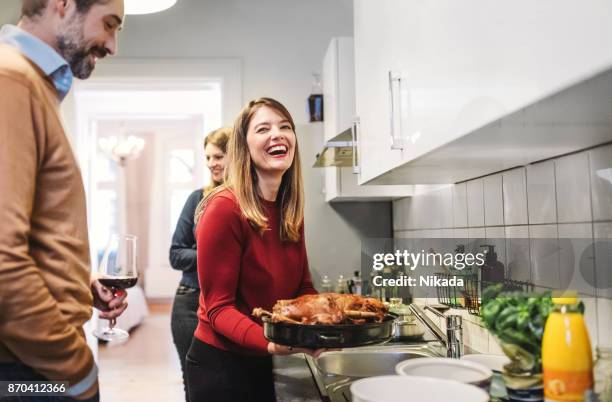 young woman smiling and holding christmas poultry in kitchen - diner plates stock pictures, royalty-free photos & images