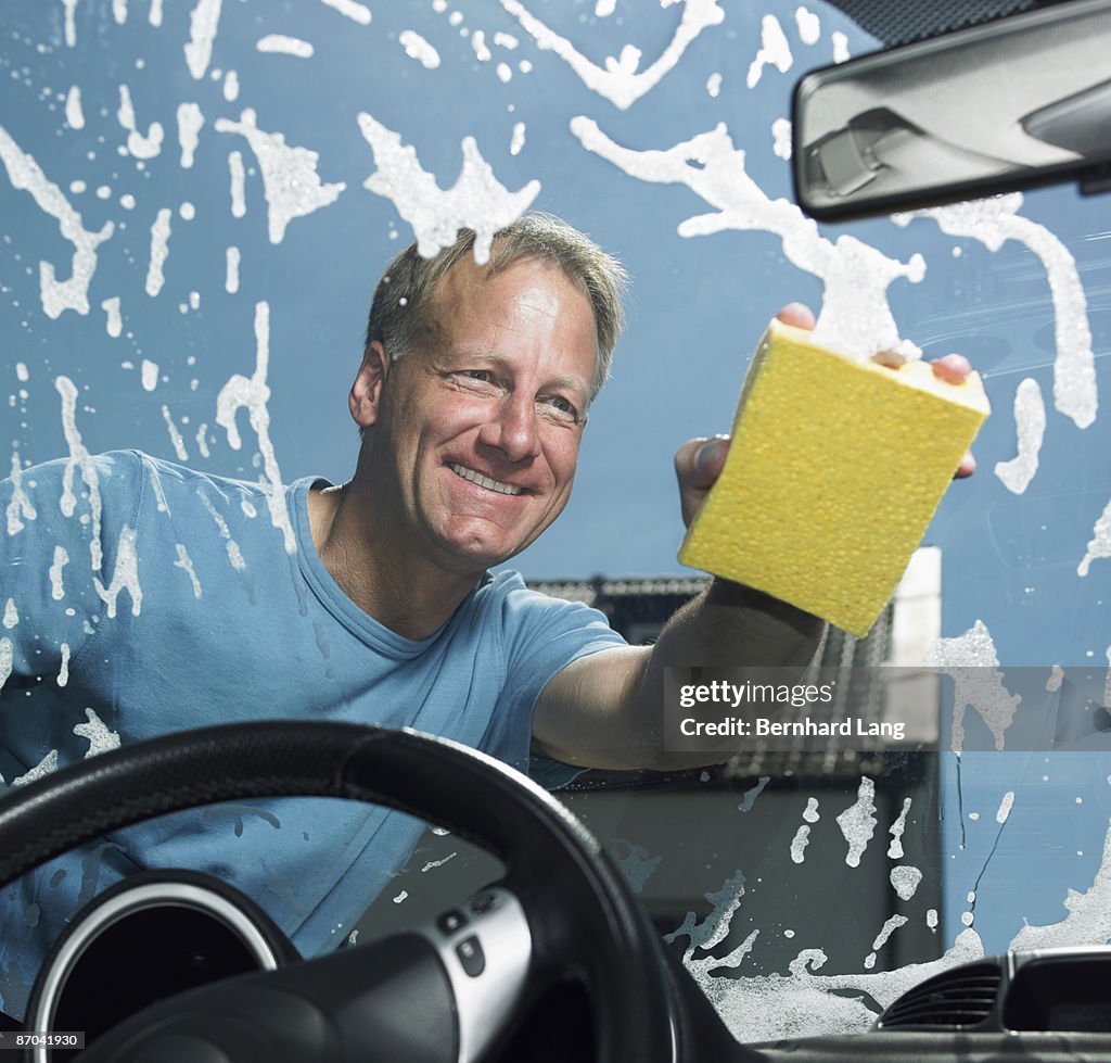 Man washing window of car