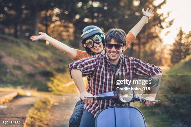 happy couple on a scooter at summer vacation - couple scooter stock pictures, royalty-free photos & images