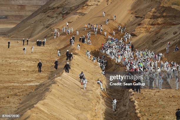 Climate activists from the group "Ende Gelaende" charge across a ditch past riot police into the Hambach open-pit coal mine on November 5, 2017 near...