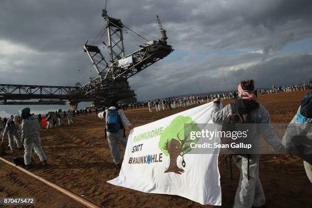 Climate activists from the group "Ende Gelaende" stand near a bucket excavator after they had charged into the Hambach open-pit coal mine on November...