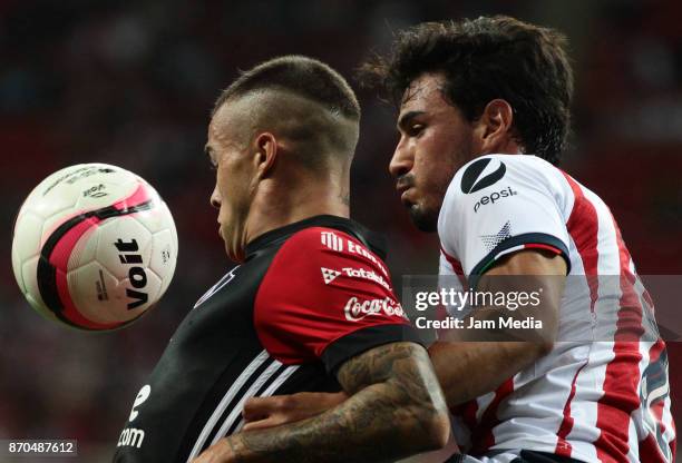 Christian Tabo of Atlas and Oswaldo Alanis of Chivas fight for the ball during the 17th round match between Chivas and Atlas as part of the Torneo...