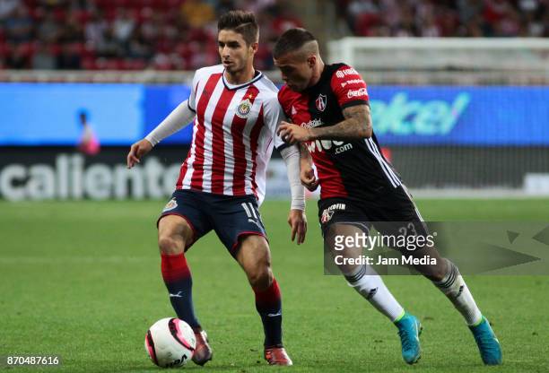 Isaac Brizuela of Chivas and Christian Tabo of Atlas fight for the ball during the 17th round match between Chivas and Atlas as part of the Torneo...