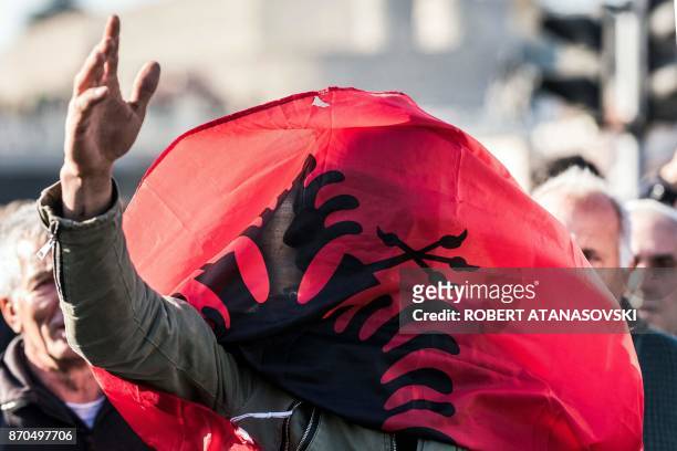 Protestor is covered with an Albanian flag as Macedonian Albanians gather in Skopje on November 5 to protest against the verdict of people convicted...