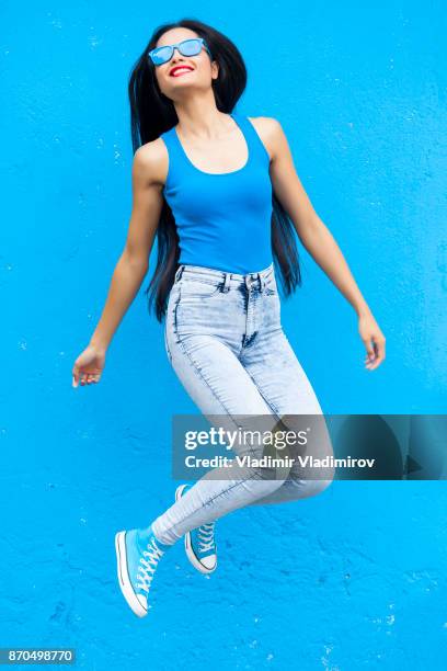 vrouw in blauwe kleur springen - multi coloured trousers stockfoto's en -beelden