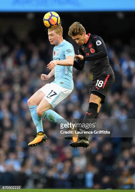 Kevin De Bruyne of Manchester City and Nacho Monreal of Arsenal battle for possession in the air during the Premier League match between Manchester...